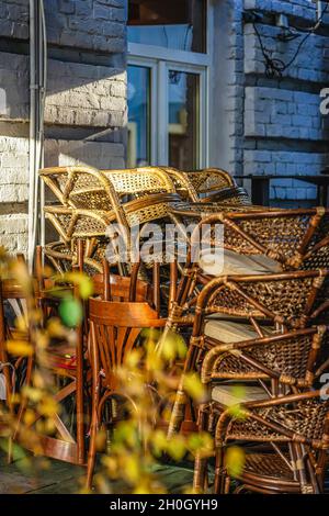 Il y a un tas de chaises en bois dans le café de la rue.Fin de la saison estivale, chute des feuilles, ambiance d'automne, concept de tristesse Banque D'Images