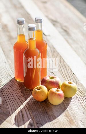 Jus de pomme naturellement nuageux, fait maison dans une bouteille de jus avec des pommes à la lumière de l'automne Banque D'Images