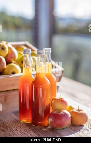 Jus de pomme naturellement nuageux, fait maison dans une bouteille de jus avec des pommes dans une caisse de pomme avec lumière d'automne Banque D'Images