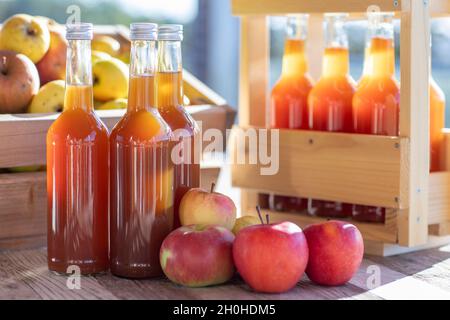 Jus de pomme naturellement nuageux, fait maison dans une bouteille de jus avec des pommes dans une caisse de pomme avec lumière d'automne Banque D'Images