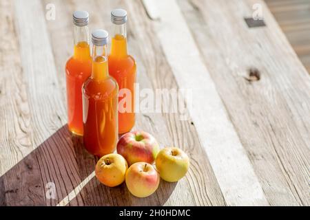 Jus de pomme naturellement nuageux, fait maison dans une bouteille de jus avec des pommes à la lumière de l'automne Banque D'Images