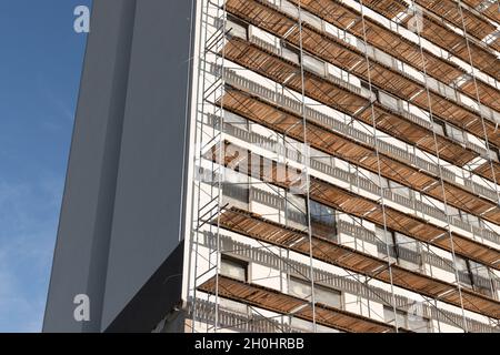 Un bâtiment moderne est en construction.Échafaudage en métal et murs blancs sous ciel bleu par temps ensoleillé Banque D'Images