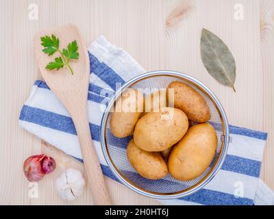 Des pommes de terre biologiques frais dans panier avec herbes ail échalote,,le persil et les feuilles de laurier sur table en bois rustique. Préparation à la cuisson. Banque D'Images