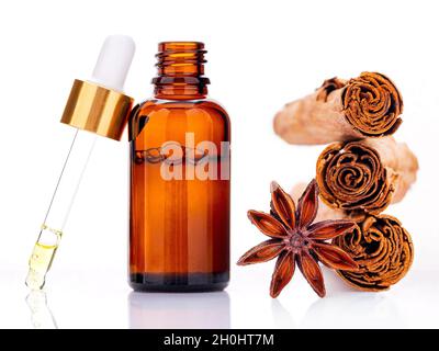 Bouteille d'huile essentielle à la cannelle avec bâtonnets de cannelle Ceylan et étoile anis isolée sur fond blanc . Banque D'Images