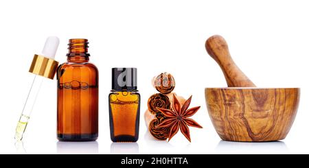 Bouteille d'huile essentielle à la cannelle avec bâtonnets de cannelle Ceylan et étoile anis isolée sur fond blanc . Banque D'Images