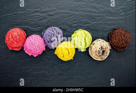 Divers de crème glacée saveur de bleuets ,balle ,lime ,pistache ,amandes chocolat et vanille, orange sur fond noir en noir . L'été et doux Banque D'Images