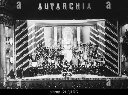 "La grande organisation italienne des travailleurs agricoles" a tenu une réunion de masse au Teatro Adriano à Rome le samedi 18 décembre 1937, au cours de laquelle les objectifs de l'effort italien d'autosuffisance en matière d'alimentation ont été connus.La photo montre la scène du théâtre, rempli de fonctionnaires, pendant la réunion.En bas de la scène se trouve un slogan programmatique: ''Gli Italiani devono vivere intensamente nella mistica dell'autarchia''.[traduction automatique]' Banque D'Images