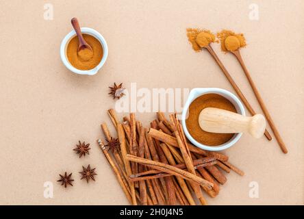 Composition de bâton de cannelle et la cannelle en poudre dans un mortier blanc à la badiane et cuillère en bois sur fond brun . Banque D'Images