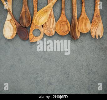 Divers ustensiles de cuisine en bois frontière. Cuillères en bois et spatule en bois sombre sur fond de pierre avec une télévision lay et copie espace. Banque D'Images