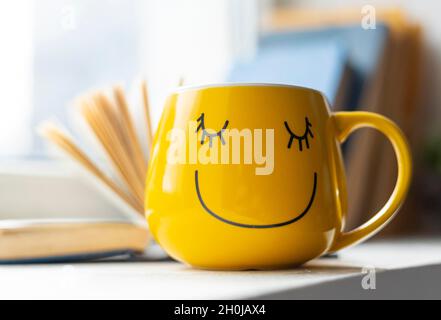 Livre ouvert et tasse jaune smiley Banque D'Images