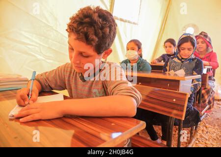 11 octobre 2021, Idlib, gouvernorat d'Idlib, Syrie : Idlib,Syrie.11 octobre 2021.Des enfants de familles syriennes déplacées assistent à des cours dans les 'tentes de petits' des camps de déplacés dans le nord d'Idlib.La nouvelle année universitaire commence dans le gouvernorat d'Idlib au nord-ouest de la Syrie, dans les camps et dans les bâtiments scolaires, avec plus de ressources pour lutter contre la pandémie de Covid-19.En plus des problèmes de sécurité et des obstacles auxquels les enfants syriens doivent toujours faire face depuis le début du conflit dans le pays, l'épidémie de coronavirus de l'an dernier a entravé une plus grande extension de l'accès des enfants à l'éducation (CRED) Banque D'Images