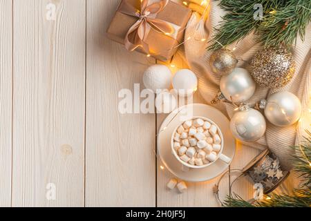 Ambiance de Noël avec une tasse de café et des décorations de Noël sur un fond clair à la lumière des lumières allumées. Banque D'Images