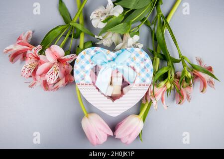 vue de dessus d'une boîte cadeau en forme de coeur avec guimauve et alstroemeria de couleur rose et blanc et fleurs de tulipe sur fond blanc Banque D'Images