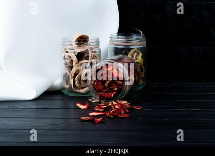 vue latérale de différentes tranches de fruits secs dans des pots de verre fraise banane et kiwi sur fond noir avec espace de copie Banque D'Images