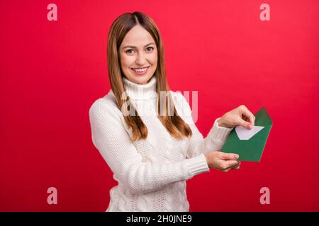 Portrait d'une femme gaie attrayante mettant la liste de lettres à enveloppe isolée sur fond rouge vif Banque D'Images