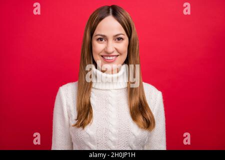 Portrait d'une jolie femme gaie à cheveux bruns portant un pull-over de saison chaude isolé sur fond rouge vif Banque D'Images