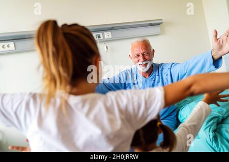 Le grand-père heureux se remet du coronavirus est visité par ses petits-enfants Banque D'Images