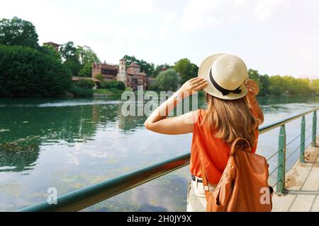 Fille de voyageur tenant son chapeau à la découverte du château caché dans le parc.Jeune femme se relaxant et respirant sur la promenade de la rivière. Banque D'Images