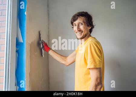 Plasterer amélioration à la maison ouvrier de main avec couteau à mastic travaillant sur le remplissage de mur d'appartement Banque D'Images