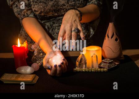 Détail des mains d'une femme avec une boule de cristal pour regarder dans l'avenir.Concept d'une session de divination avec une boule de cristal. Banque D'Images