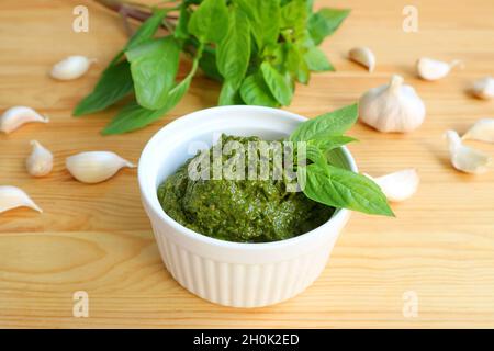 Délicieuse sauce pesto de basilic frais maison dans un bol blanc avec ses ingrédients en toile de fond Banque D'Images