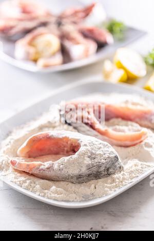 Préparation du poisson frais avant la friture en l'emballant dans la farine. Banque D'Images