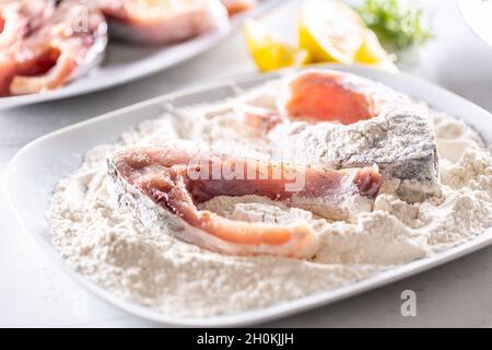 Préparation du poisson frais avant la friture en l'emballant dans la farine. Banque D'Images