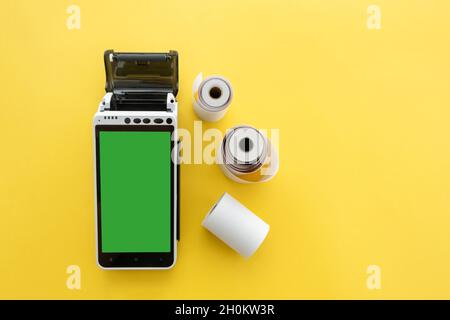 Terminal de paiement POS avec écran tactile avec rouleaux de ruban adhésif sur fond jaune.Concept de service de maintenance du terminal de point de vente Banque D'Images