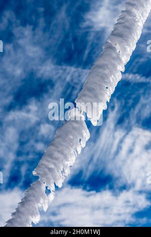 Gros plan d'une corde recouvrant de givre par une journée froide d'hiver sur un fond de ciel bleu avec des nuages Banque D'Images