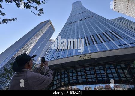 Pékin, Chine.12 octobre 2021.Une femme portant un masque prend des photos du bâtiment China Zun avec son téléphone portable à Beijing.le 12 octobre, les dernières perspectives économiques mondiales publiées par le Fonds monétaire international (FMI) ont montré que la valeur prévue du taux de croissance économique mondial en 2021 a été légèrement réduite à 5.9%,et la valeur prévue en 2022 est restée inchangée à 4.9 %.Le FMI prévoit que le PIB de la Chine pourrait croître de 8% et celui des États-Unis de 6% en 2021.(Photo de Sheldon Cooper/SOPA Images/Sipa USA) crédit: SIPA USA/Alay Live News Banque D'Images