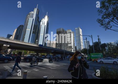 Pékin, Chine.12 octobre 2021.Une femme qui porte un masque parle au téléphone, se promène près du quartier central des affaires de Pékin.le 12 octobre, les dernières perspectives économiques mondiales publiées par le Fonds monétaire international (FMI) ont montré que la valeur prévue du taux de croissance économique mondial en 2021 a été légèrement réduite à 5.9%,et la valeur prévue en 2022 est restée inchangée à 4.9 %.Le FMI prévoit que le PIB de la Chine pourrait croître de 8% et celui des États-Unis de 6% en 2021.(Photo de Sheldon Cooper/SOPA Images/Sipa USA) crédit: SIPA USA/Alay Live News Banque D'Images