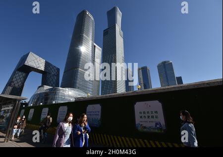 Pékin, Chine.12 octobre 2021.Des piétons portant des masques marchent le long du mur d'un chantier de construction près du quartier central des affaires, à Beijing.le 12 octobre, les dernières perspectives économiques mondiales publiées par le Fonds monétaire international (FMI) ont montré que la valeur prévue du taux de croissance économique mondial en 2021 a été légèrement réduite à 5.9%,et la valeur prévue en 2022 est restée inchangée à 4.9 %.Le FMI prévoit que le PIB de la Chine pourrait croître de 8% et celui des États-Unis de 6% en 2021.(Photo de Sheldon Cooper/SOPA Images/Sipa USA) crédit: SIPA USA/Alay Live News Banque D'Images