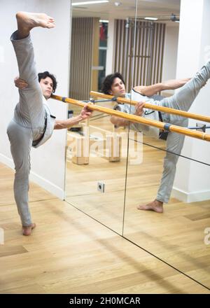 Homme danseur danse professeur de gravure dans la salle de fitness studio faisant le bar avancé de flexibilité extensible posture. Banque D'Images