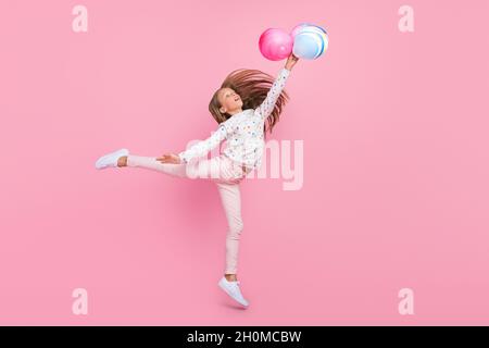 Photo d'inspiration flexible petite dame jump tenir ballons look up porter chemise à pois isolé couleur rose fond Banque D'Images