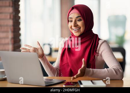 Femme musulmane émotive ayant un entretien d'emploi en ligne, à l'aide d'un ordinateur portable Banque D'Images