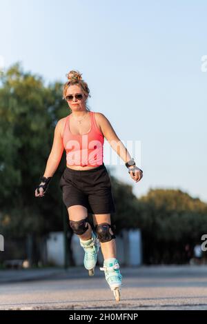 Femme avec équipement de protection de patinage avec le patinage en ligne à l'extérieur Banque D'Images