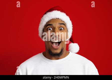 Gros plan d'un homme noir surprise dans un chapeau de père noël Banque D'Images