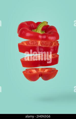 Idée minimale avec des tranches de poivron mûr frais flottant dans l'air isolé sur fond turquoise.Concept créatif de la nourriture, des légumes Banque D'Images