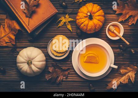Thé au citron chaud avec feuillage d'automne et citrouilles, livres et biscuits sur fond de bois Banque D'Images