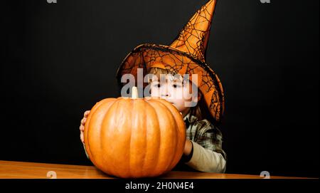 Joyeux Halloween.Petit garçon en chapeau de sorcière avec citrouille d'halloween.Enfant avec Jack-o-lanterne. Banque D'Images