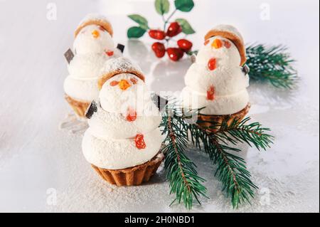 Trois bonhommes de neige en meringue douce avec décorations de Noël.Biscuits originaux avec guimauves et meringue sur la table de Noël.Cookies dans le Banque D'Images