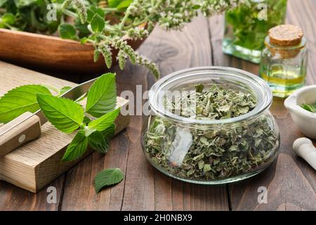 Pot de feuilles de menthe séchées.Feuilles de menthe poivrée fraîche sur une planche à découper.Blossom Mentha piperita plantes médicinales, bouteilles d'huile essentielle de menthe et infu Banque D'Images