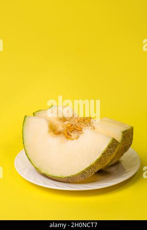 trois tranches de melon sur une plaque sur fond jaune, espace de copie. Banque D'Images