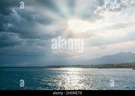 Ciel ensoleillé avec nuages en mer.Station ville et montagnes à l'horizon.Soleil matinal sur l'océan bleu.Superbes points d'eau.Voyages, vacances d'été, tourisme. Banque D'Images