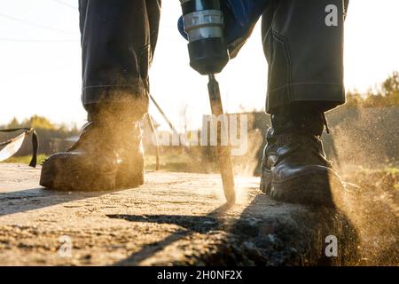 Un installateur mâle travaille avec un marteau perforateur.Travaux de construction Banque D'Images