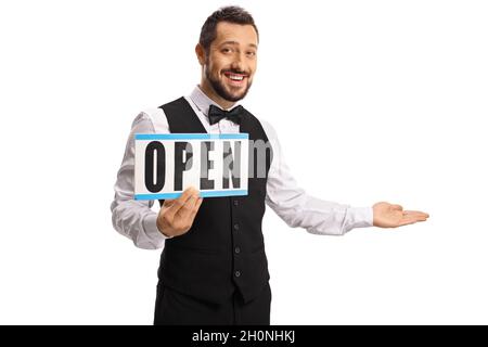 Gai jeune serveur tenant un panneau ouvert et gesturant accueil isolé sur fond blanc Banque D'Images