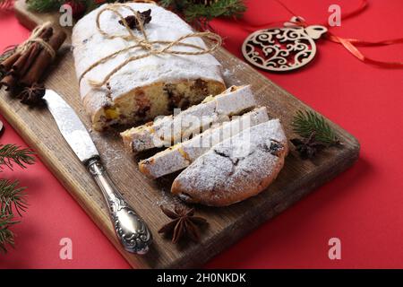 Noël savoureux stollen avec des fruits secs, des baies et des noix sur fond rouge. Gâteries traditionnelles allemandes. Gros plan Banque D'Images