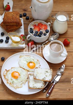 Œufs brouillés avec sandwiches ricotta, muesli avec lait et fruits sur une assiette blanche Banque D'Images