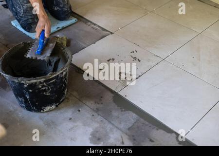 Le constructeur met les carreaux sur le sol, la réparation Banque D'Images