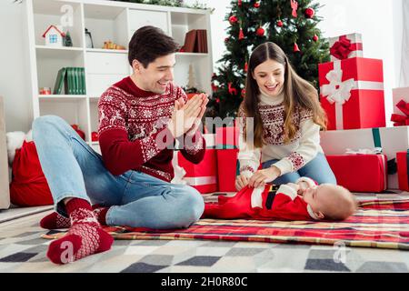 Photo de parents joueurs divertir bébé petit garçon bébé ont plaisir vêtements chandail dans la maison de Noël décorée à l'intérieur Banque D'Images